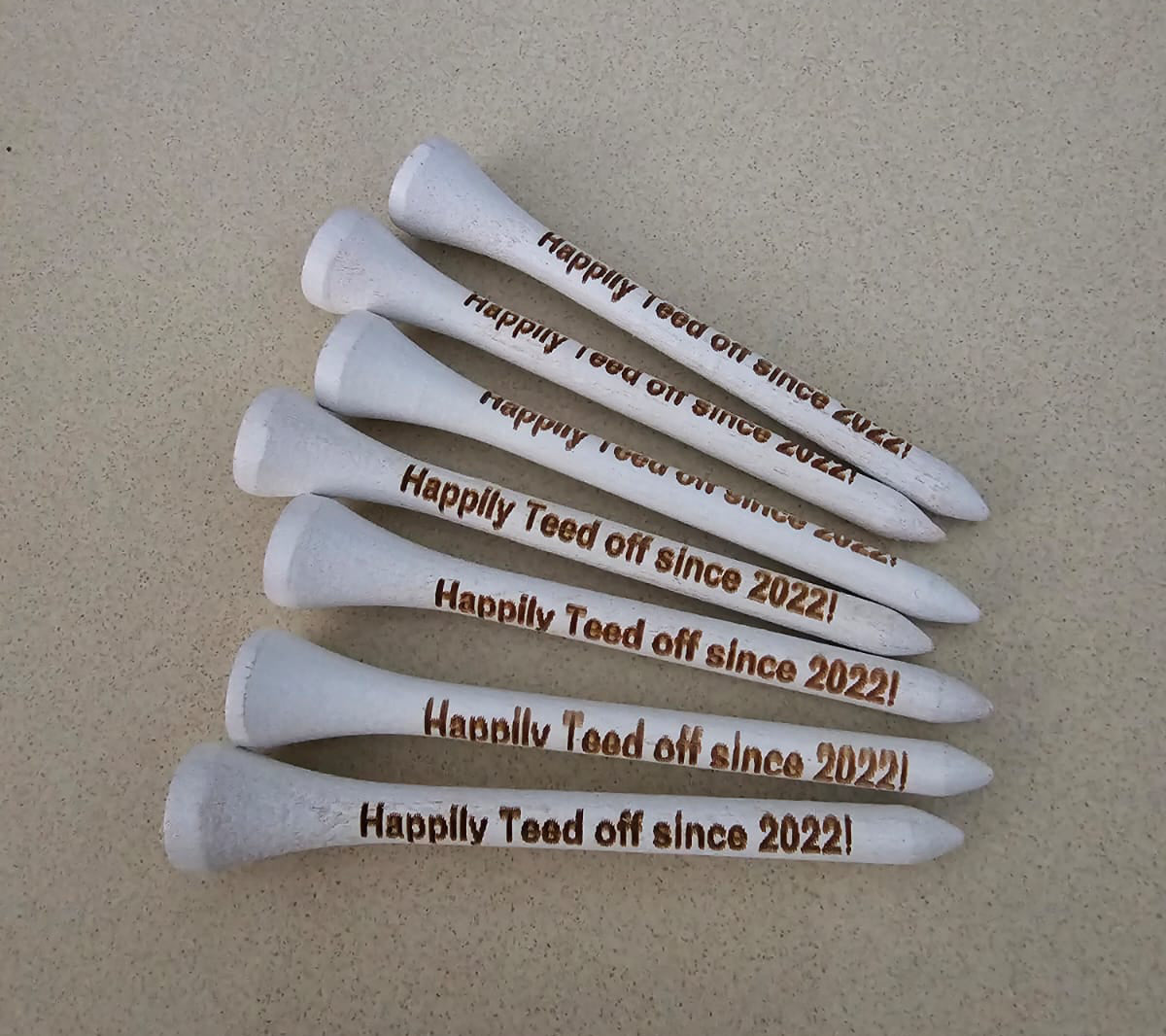 White golf tees with 'Happily Teed off since 2022!'